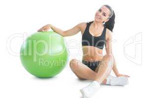 Cute slender woman posing sitting on the floor next to an exerci