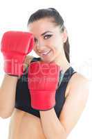 Joyful brunette woman wearing boxing gloves smiling at camera