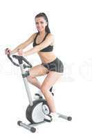 Cheerful ponytailed sporty woman training on an exercise bike