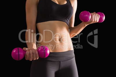 Slender active woman lifting pink dumbbells