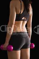Rear view of slender woman holding pink dumbbells