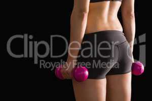 Rear view of slim woman wearing sportswear holding pink dumbbell