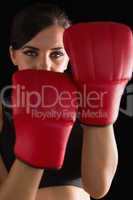 Front view of young sporty woman posing wearing boxing gloves