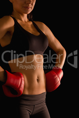 Mid section of young sporty woman posing and wearing boxing glov
