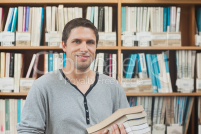 Attractive mature student standing in a library holding some boo