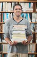Adult student posing holding a stack of books