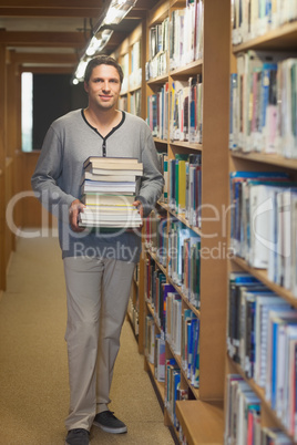 Attractive male librarian carrying a pile of books