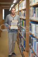 Attractive male librarian carrying a pile of books