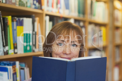 Peaceful mature woman holding a book in a library