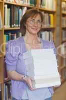 Mature female librarian posing holding a pile of books