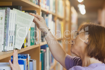 Mature female librarian searching a book