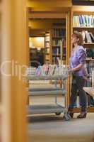 Serious female librarian pushing a cart