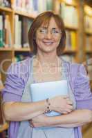 Mature female librarian posing in library holding a tablet