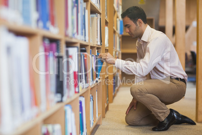 Handsome casual man cowering in front of bookshelves