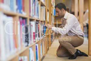Handsome casual man cowering in front of bookshelves