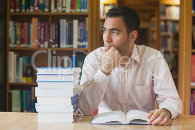 Attractive man sitting in library in front of an opened book