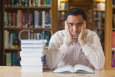 Handsome man sitting in front of an opened book in library