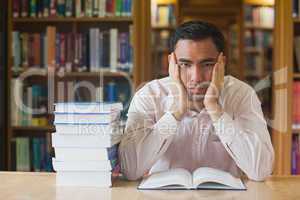 Handsome man sitting in front of an opened book in library