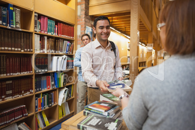 Mature female librarian handing a book to young man