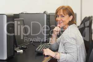 Cheerful female mature student sitting in computer class