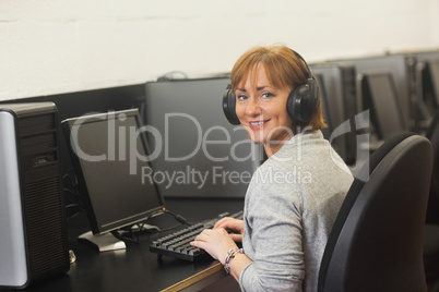 Mature woman working on computer while listening to music