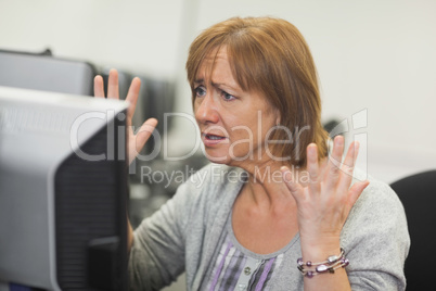 Annoyed mature woman working on computer