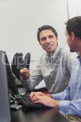 Two friendly men talking sitting in front of a computer