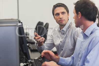 Two handsome men talking while sitting in computer class