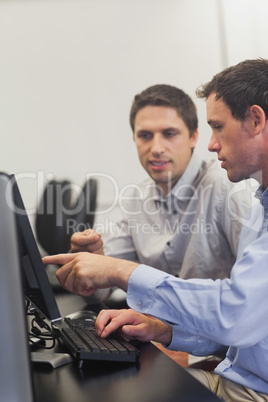 Two mature men talking while sitting in front of computer