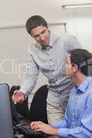 Attractive teacher talking to his student in computer class