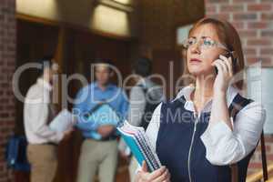 Female mature student phoning standing in corridor