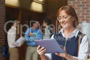 Amused smiling mature woman using her tablet