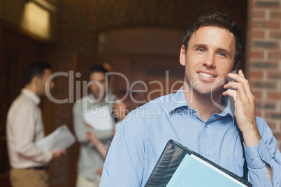 Attractive male mature student phoning with his smartphone