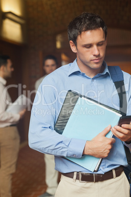 Serious handsome mature student using his smartphone