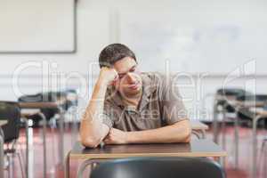 Tired male mature student sitting in class room