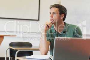 Thoughtful handsome mature student sitting in classroom while le