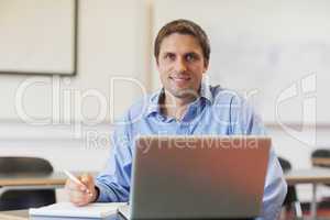 Handsome mature student learning and sitting in classroom