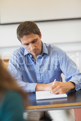 Handsome concentrated mature student sitting in classroom