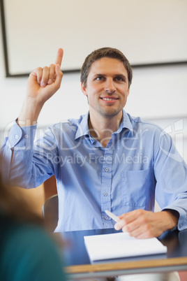 Amused male mature student raising his hand