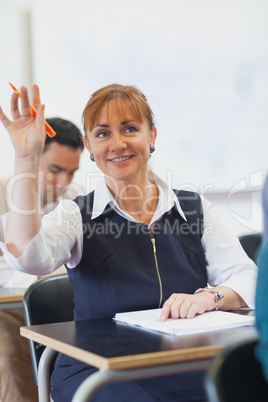 Cheerful female mature student raising her hand