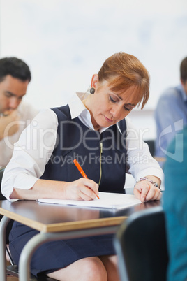 Concentrated female mature student sitting in classroom