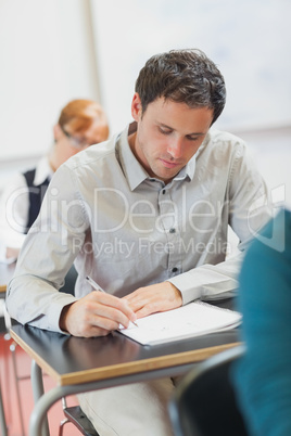 Concentrated male mature student sitting in classroom with class