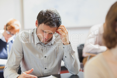 Concentrating handsome mature student sitting in classroom with