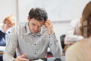 Concentrating handsome mature student sitting in classroom with