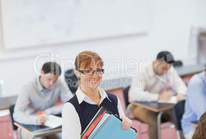 Female teacher posing in her classroom holding some files