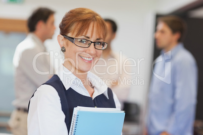 Portrait of female mature student posing in classroom holding so