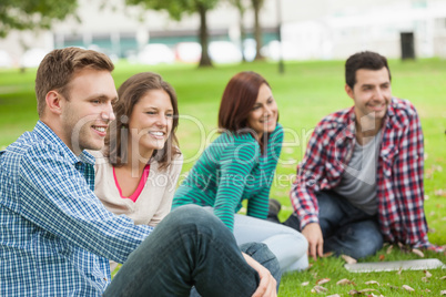 Casual happy students sitting on the grass laughing