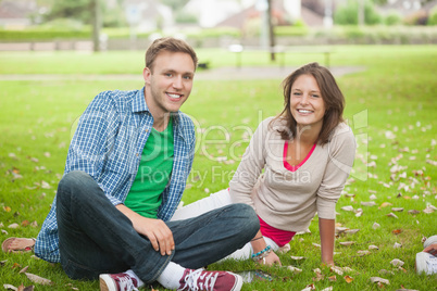 Casual smiling students sitting on the grass