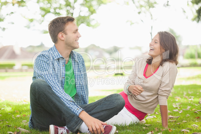 Casual laughing students sitting on the grass