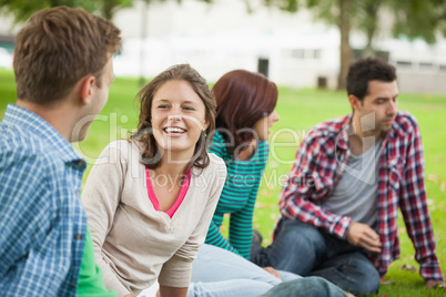 Casual laughing students sitting on the grass chatting